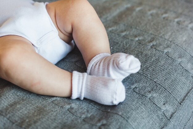 Gambe di un neonato in calzini bianchi, il bambino giace su una coperta sul letto
