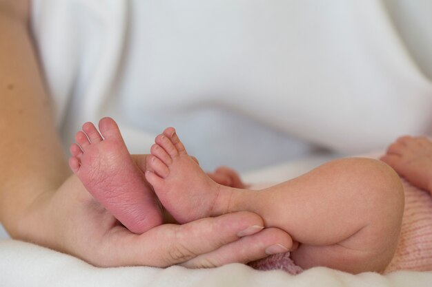 Gambe di un neonato nelle mani della madre