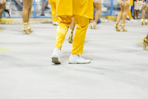 Gambe di un sambista che balla con pantaloni gialli e scarpe bianche al sambodromo da marques de sapucai a Rio de Janeiro