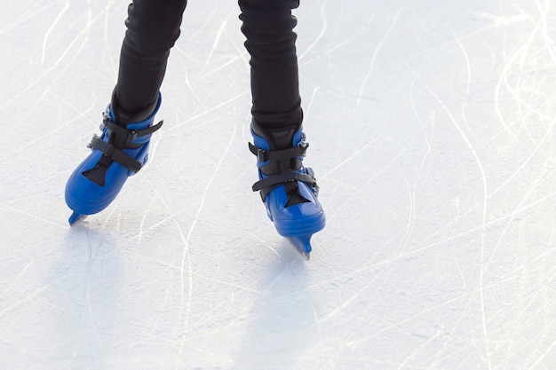 Gambe di un uomo di pattinaggio su una pista di pattinaggio. Hobby e sport. Vacanze e attività invernali.