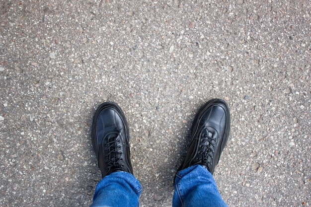 Gambe di un uomo in scarpe sul marciapiede in jeansPOV