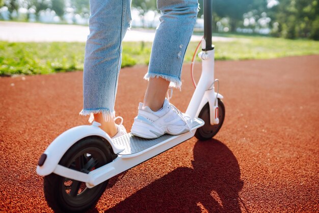 Gambe di una donna che guida uno scooter elettrico concetto di trasporto ecologico