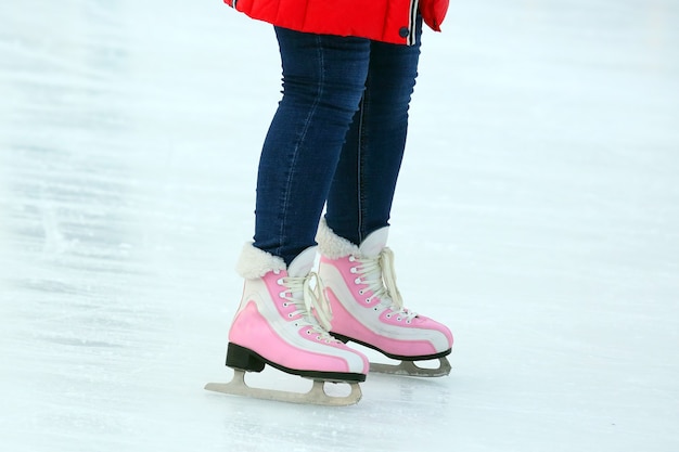 Gambe di una donna che pattina su una pista di pattinaggio sul ghiaccio. Hobby e sport. Vacanze e attività invernali