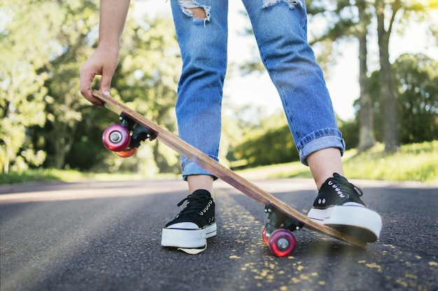 Gambe di una donna con lo skateboard sulla strada