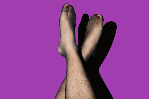 gambe di una persona non binaria che indossa collant su uno sfondo viola concetto di non binario