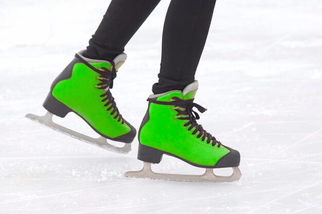 Gambe di una ragazza che pattina su una pista di pattinaggio sul ghiaccio. Hobby e sport. Vacanze e attività invernali