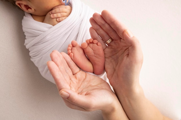 Gambe dita dei piedi piedi e talloni di un neonato Con le mani dei genitori padre madre tiene delicatamente le gambe del bambino Macrofotografia primo piano Foto in bianco e nero Foto di alta qualità