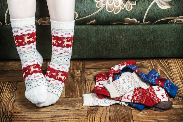 Gambe femminili di Natale in calze sullo sfondo del parquet