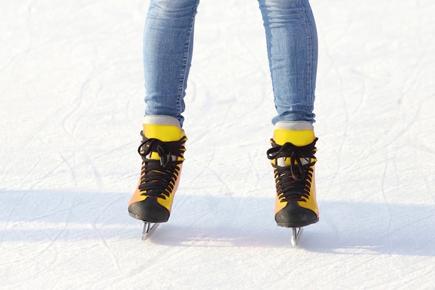 Gambe femminili in pattini su una pista di pattinaggio. Sport e divertimento. Riposo e vacanze invernali.