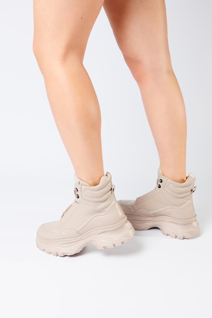 Gambe femminili in scarpe in pelle beige della nuova collezione su sfondo bianco gambe femminili in scarpe alla moda in ecopelle primavera 2022