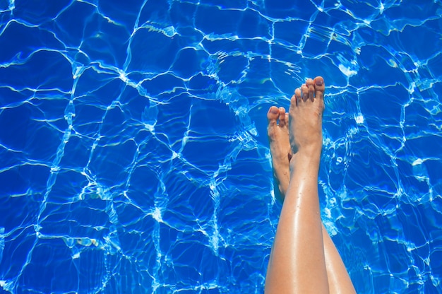 Gambe femminili nel raggruppamento di acqua blu