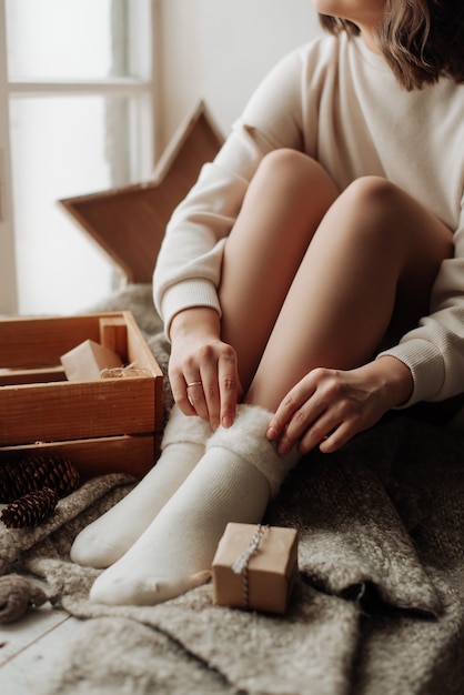 Gambe femminili nude in calzini bianchi ragazza seduta sul letto