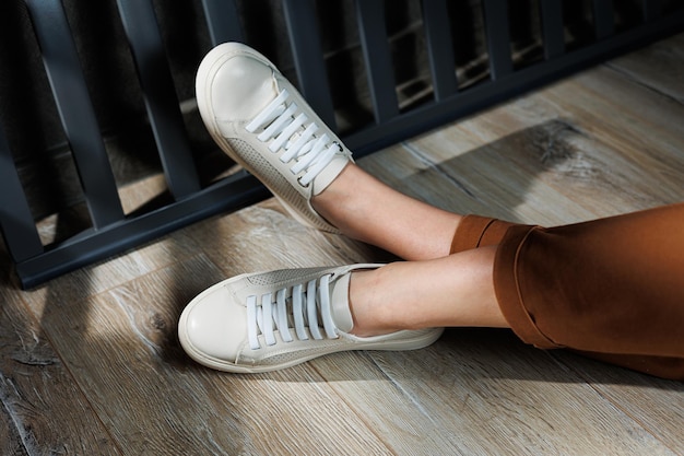 Gambe femminili sottili in pantaloni close-up in scarpe da ginnastica casuali beige scarpe di pelle da donna