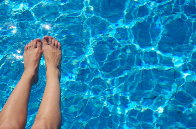 Gambe femminili sullo sfondo della piscina Struttura dell'acqua a destra dello spazio aperto con riflessi di luce solare