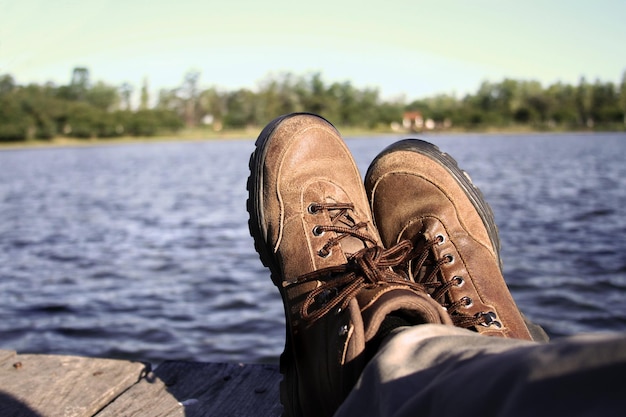 Gambe incrociate, scarpe da trekking. Persona rilassata in un paesaggio naturale. Meditazione e pensiero positivo