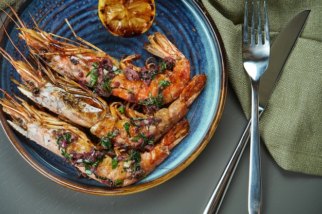 Gamberetti arrostiti della tigre con il limone in un piatto blu su una tavola di legno. Vista dall'alto di frutti di mare di lusso con spazio di copia. Disteso