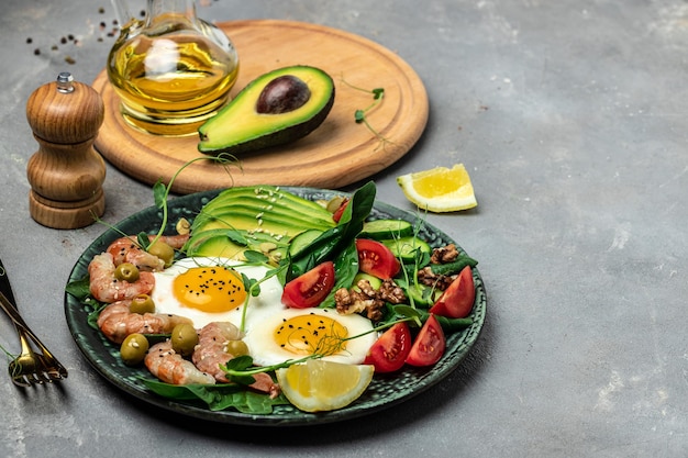 Gamberetti gamberi morbido uovo fritto insalata fresca pomodori cetrioli e avocado su uno sfondo chiaro Dieta chetogenica colazione Keto paleo pranzo Vista dall'alto