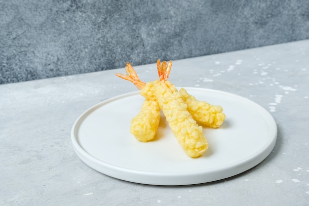 Gamberetti in tempura su un piatto bianco. Consegna del cibo di cucina asiatica