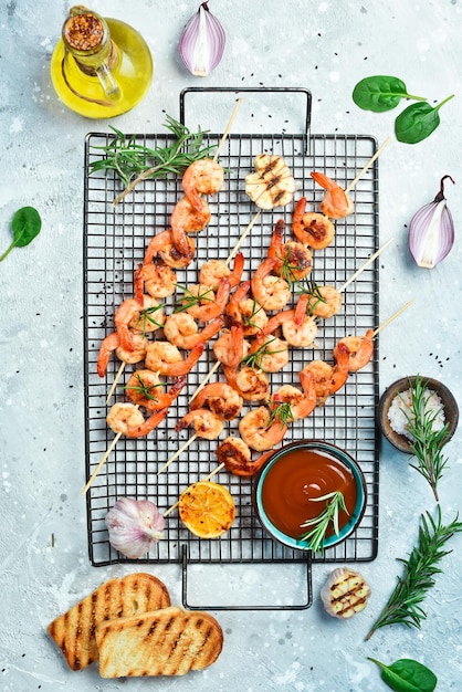 Gamberi alla griglia su spiedini con limone e aglio Frutti di mare su uno sfondo di pietra