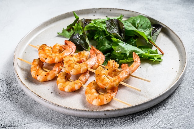 Gamberi arrostiti, gamberi su spiedini con insalata di spinaci.