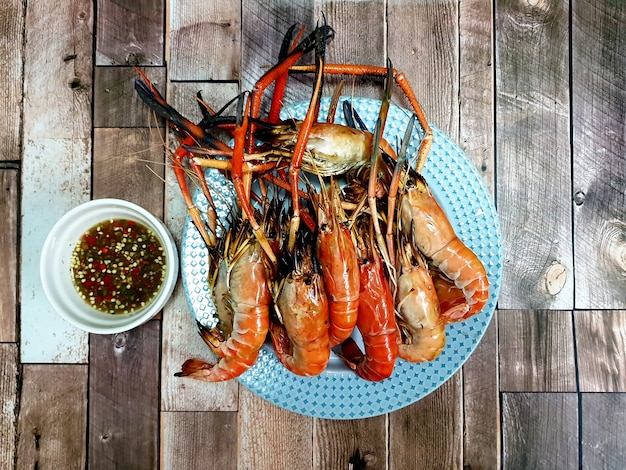 Gamberi di fiume alla griglia con salsa di frutti di mare su fondo di legno