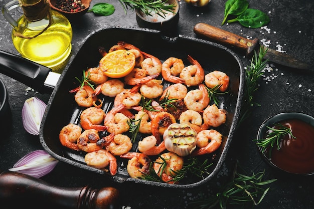 Gamberi fritti con aglio e limone in padella Frutti di mare Su uno sfondo di pietra nera