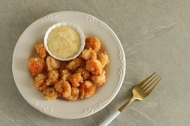 Gamberi fritti con maionese serviti in piatto bianco con forchetta