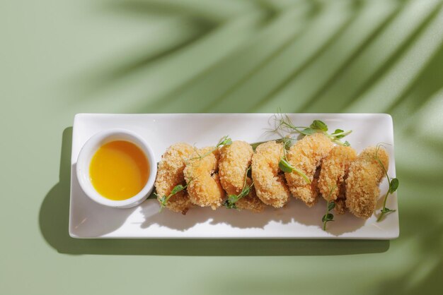 Gamberi fritti con un cocktail su uno sfondo verde chiaro con un'ombra da una vista dall'alto di una palma