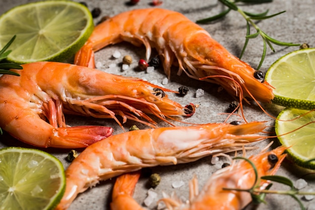 Gamberi tigre con spezie lime, limone, rosmarino e pepe nero su pietra. Gamberi freschi e gustosi pronti per essere cotti.