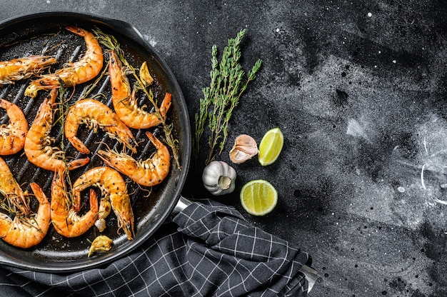 Gamberoni giganti alla griglia, gamberetti con aglio, limone, spezie in padella. Sfondo nero