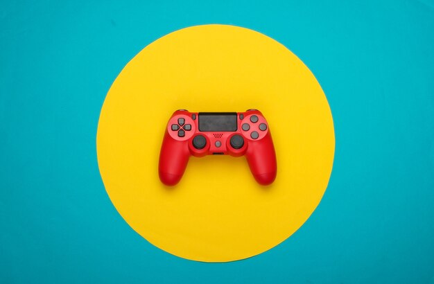 Gamepad rosso su blu con cerchio giallo.