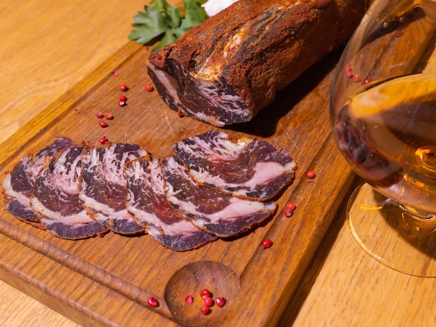 Gammon affumicato a fette su un tavolo di legno con aggiunta di erbe fresche e spezie aromatiche