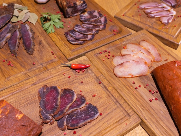 Gammon affumicato a fette su un tavolo di legno con aggiunta di erbe fresche e spezie aromatiche