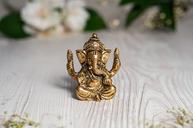 Ganapathi Ganesha Idol in bronzo decorato con fiori bianchi e foglie verdi sullo sfondo