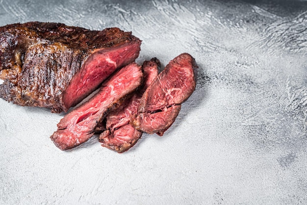 Gancio arrosto o bistecca di carne di manzo affettata Onglet su un tavolo. Sfondo bianco. Vista dall'alto. Copia spazio.