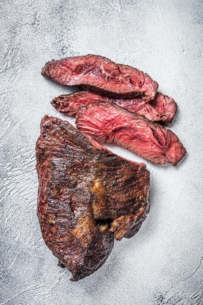 Gancio arrosto o bistecca di carne di manzo affettata Onglet su un tavolo. Sfondo bianco. Vista dall'alto.