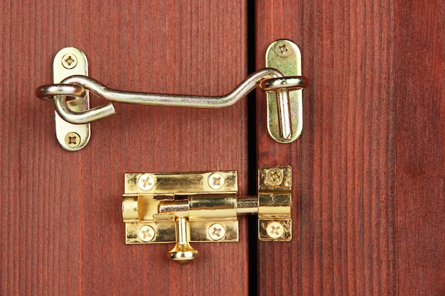 Gancio di metallo e deadbolt in un primo piano di una porta di legno