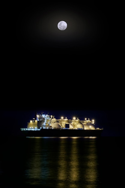 Gasatore di notte sullo sfondo del mare scuro e un ormeggio per la spedizione di GNL