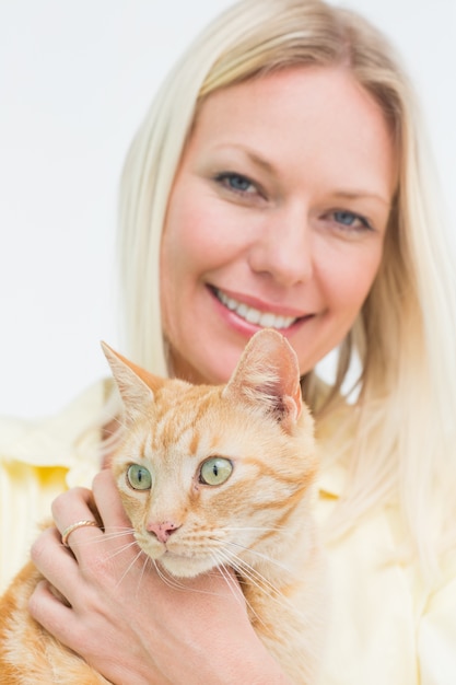 Gatto felice della holding della donna su priorità bassa bianca