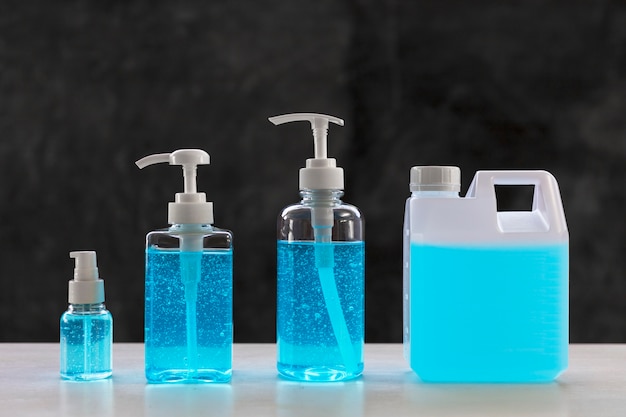 Gel di alcoli blu sul tavolo bianco e ossido di calcio. Gel igienizzante per le mani per la pulizia. Igienizzante per le mani in 3 flaconi di diverse dimensioni. e 1L. bottiglia.