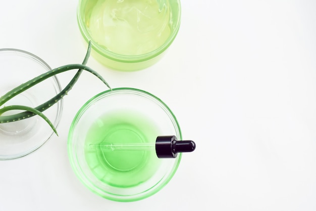 Gel di aloe, foglie di aloe vera e siero verde da ingredienti naturali su sfondo bianco. Fare cosmetici a casa