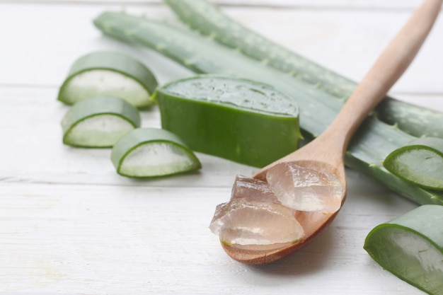 Gel di aloe vera in un cucchiaio di legno posto su un legno bianco.