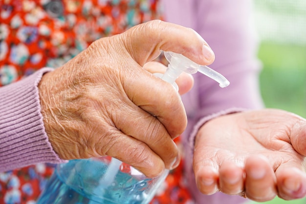 Gel disinfettante alcolico blu per donna anziana asiatica per il lavaggio delle mani per proteggere l'infezione da coronavirus