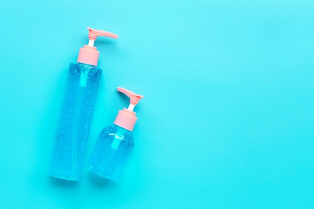 Gel disinfettante per mani alcolico in bottiglie di pompa su sfondo blu. Copia spazio