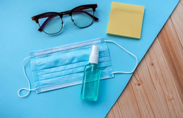 Gel igienizzante per maschera medica e occhiali da vista su sfondo blu
