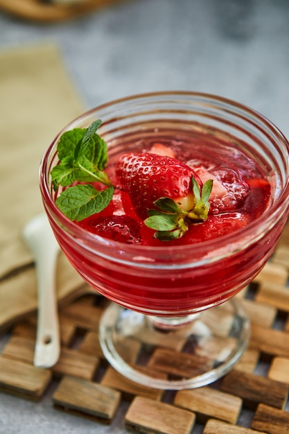 Gelatina con fragole in un bicchiere su una tavola di legno