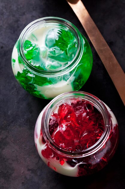 Gelatina di asperula rossa e verde in un bicchiere con salsa alla vaniglia