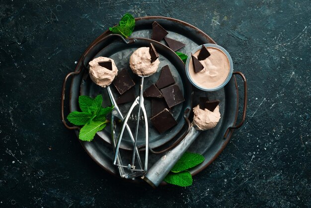 Gelato al cioccolato con menta e cioccolato Cucchiaio per gelato su uno sfondo di pietra nera vista dall'alto