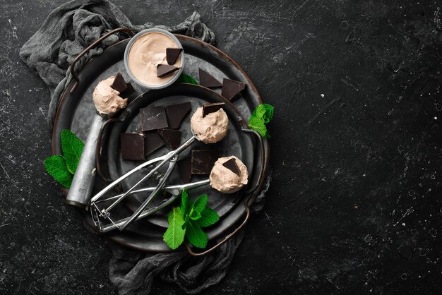 Gelato al cioccolato con menta e cioccolato Cucchiaio per gelato su uno sfondo di pietra nera vista dall'alto