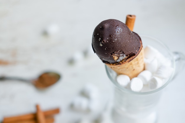 Gelato al cioccolato in un cono in un bicchiere con marshmallow su sfondo bianco. Dessert dolce sul tavolo. Composizione con gelato Snack dolce. vista dall'alto